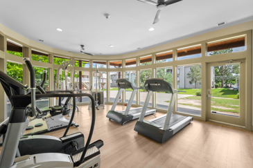 Stationary exercise equipment in a rounded community gym surrounded with windows